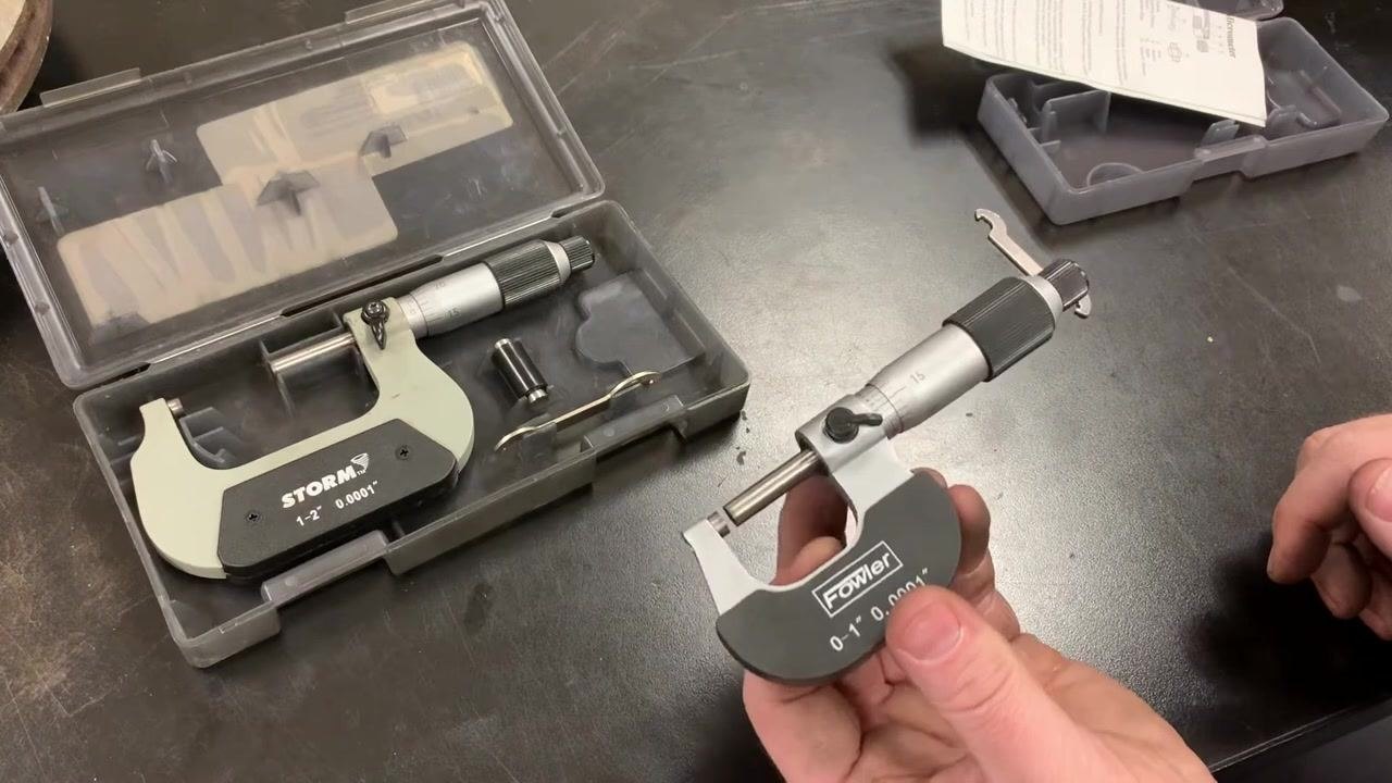 Micrometers and calibration tools laid out on a workbench, with cases open and accessories visible