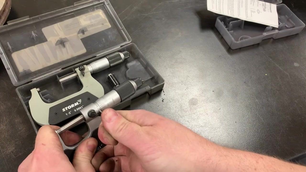 A hand using the spanner wrench to make fine adjustments to the micrometer sleeve