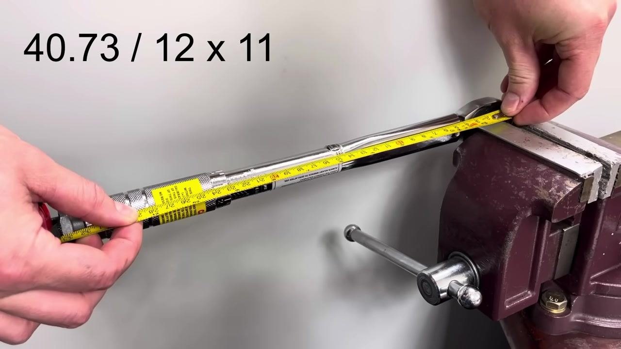 A hand grips the torque wrench, now removed from the vise and placed on a wooden workbench.