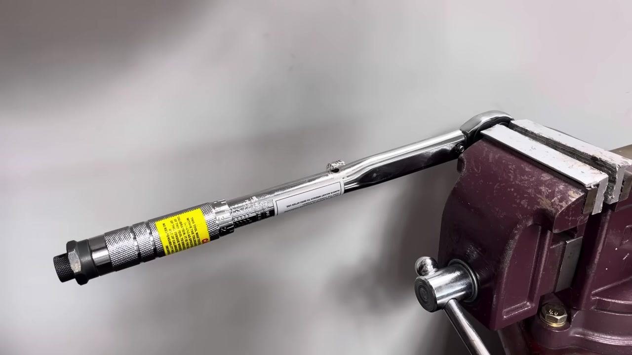The torque wrench remains in the vice, with no hands visible, indicating readiness for adjustment.
