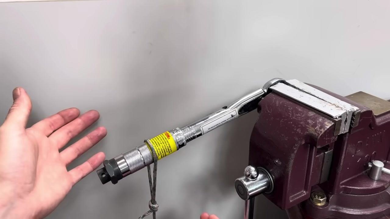 Hands gently lower the weight, attached by rope to the handle, while observing the click.