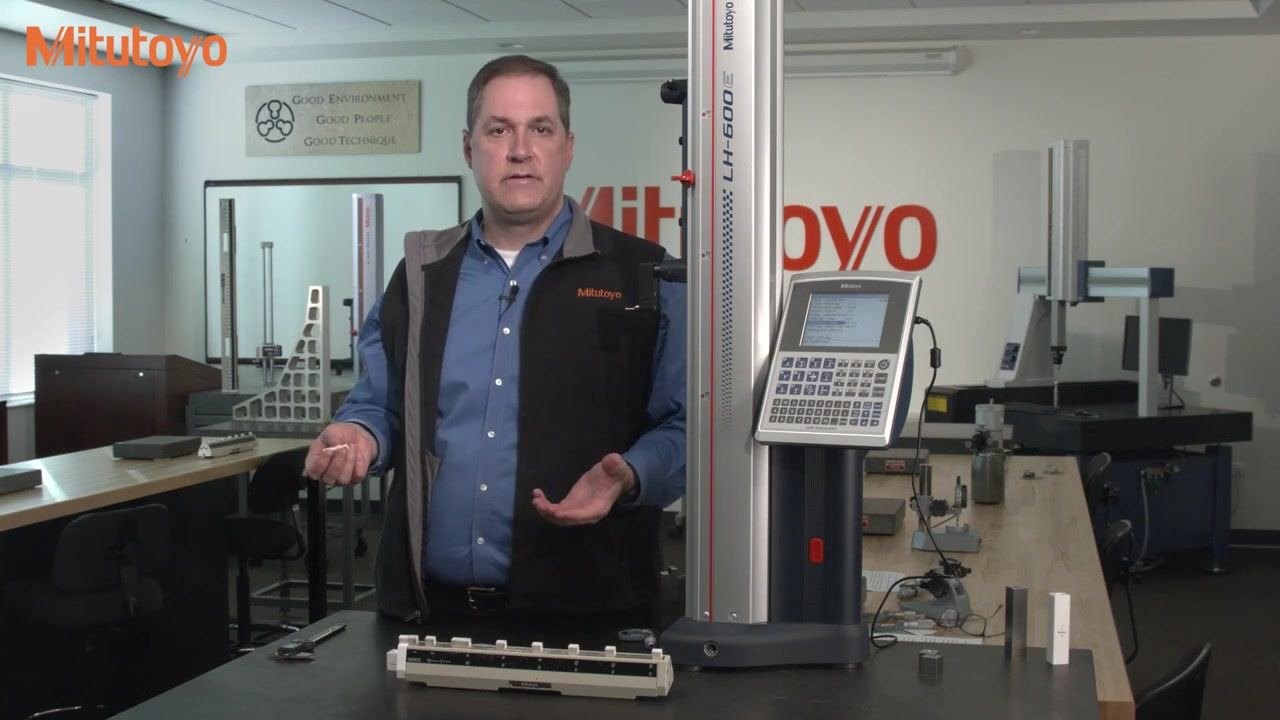 A dial caliper measuring a 0.150-inch gauge block on the calibration fixture, pointer at the 6 o'clock position