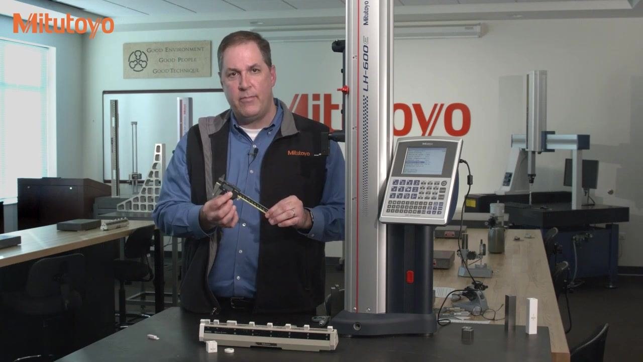 Hands using the inside jaws of a digital caliper to measure across a calibration fixture marked "INSIDE," with a 1-inch Mitutoyo gauge block visible