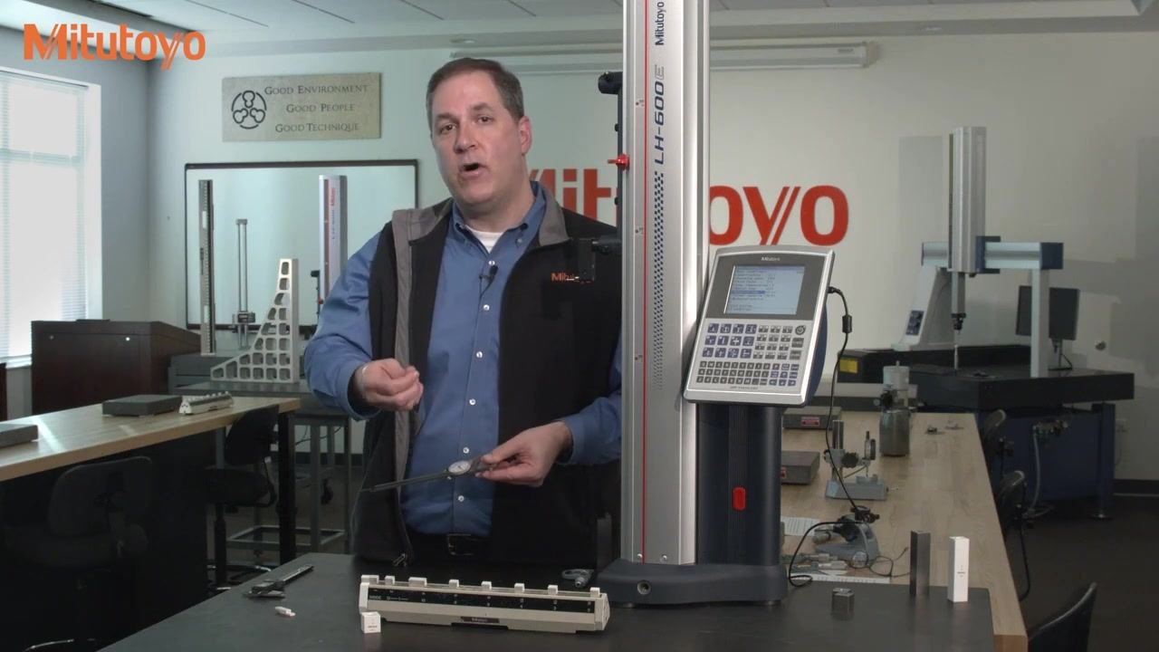 A dial caliper measuring a 0.125-inch gauge block on the calibration fixture, pointer at the 3 o'clock position
