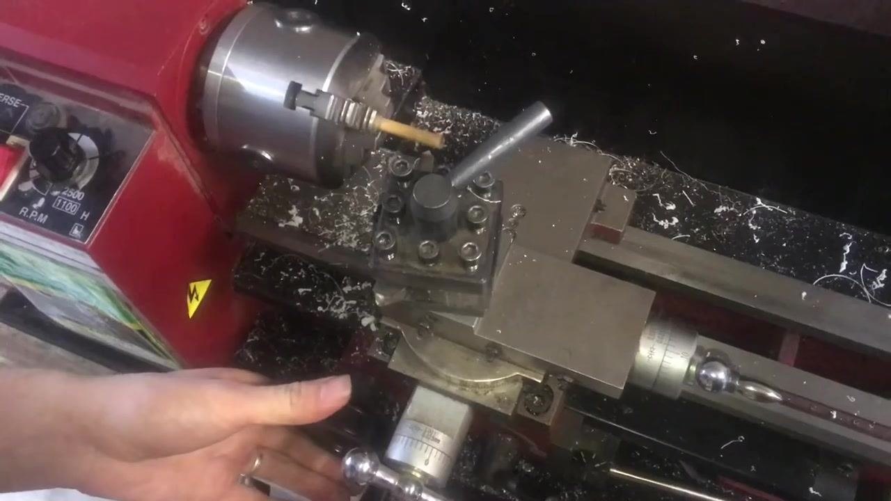 An operator's hand on the compound rest, showing the adjustment area and the angle scale.
