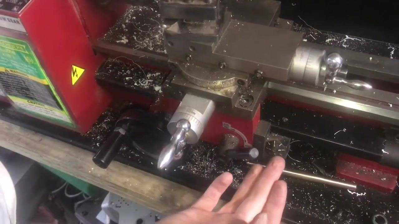 An operator's hands on the carriage handwheel and thread dial, showing the process of using the thread dial for timing.