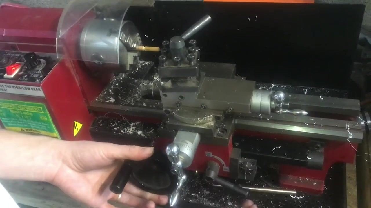 An operator's hand on the carriage handwheel, preparing to engage the threading mechanism.