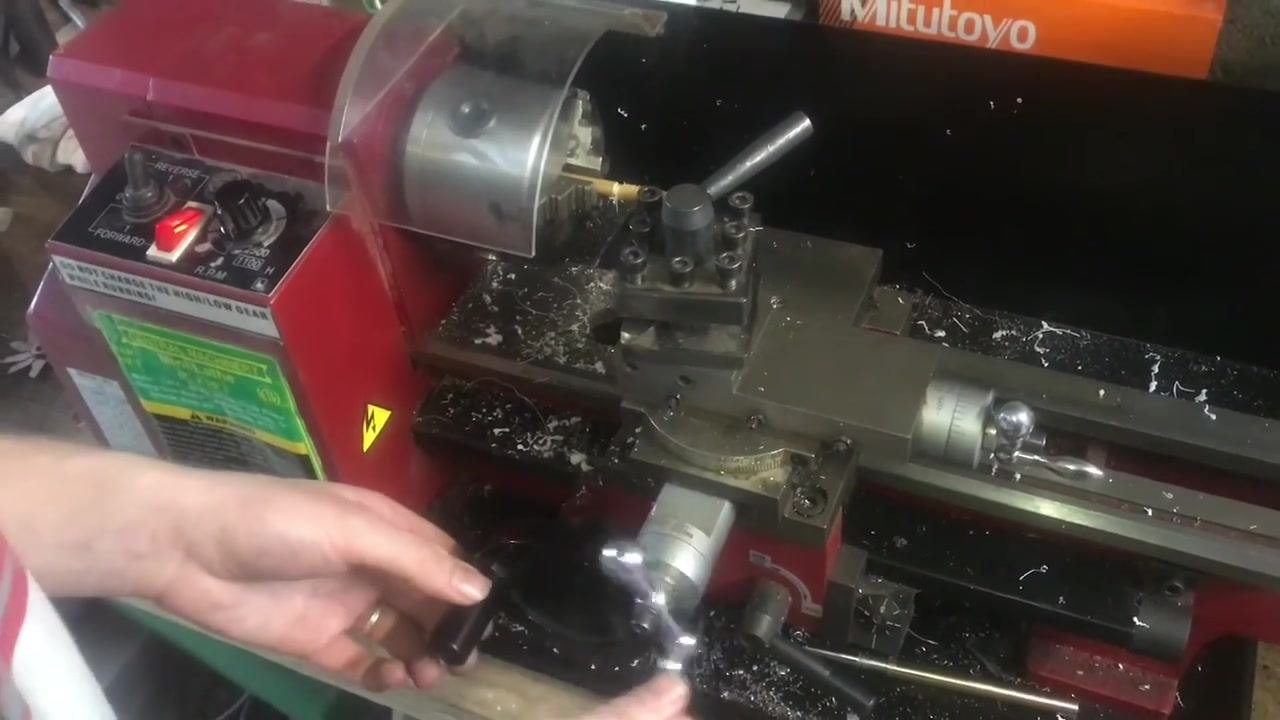 Hands on the carriage and cross-slide handwheels, preparing to feed the tool for another threading pass.