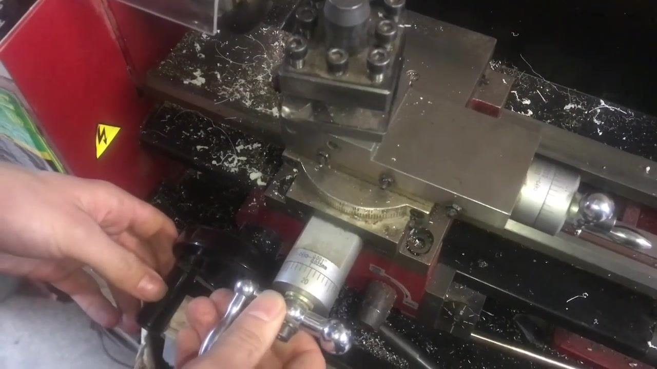 A close-up of the cross-slide dial and handwheel, with the operator adjusting for the next pass.