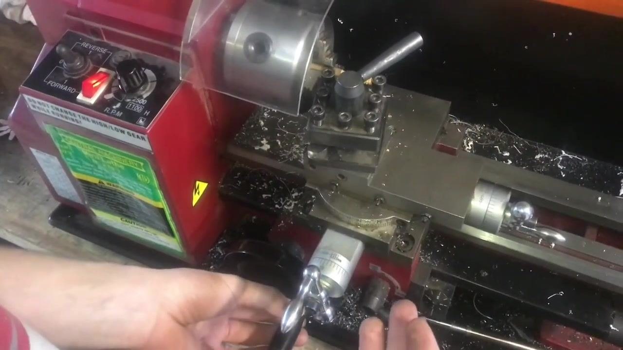 The lathe control panel with Forward illuminated, the workpiece in the chuck, the tool post engaged, wood chips visible, and thread cutting in progress.