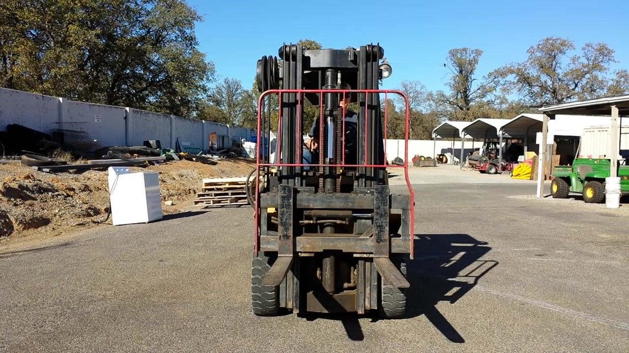 View from the operator's seat showing the mast and forks being raised, with the ground and part of the fork visible through the mast.