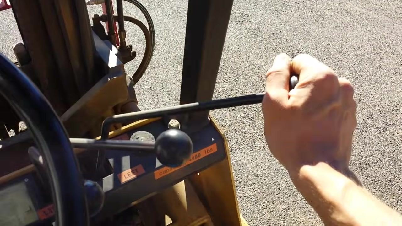 Close-up view of a hand operating the rightmost control lever on a forklift, with the "LEFT" and "cap 4000 lbs" labels visible on the control panel.
