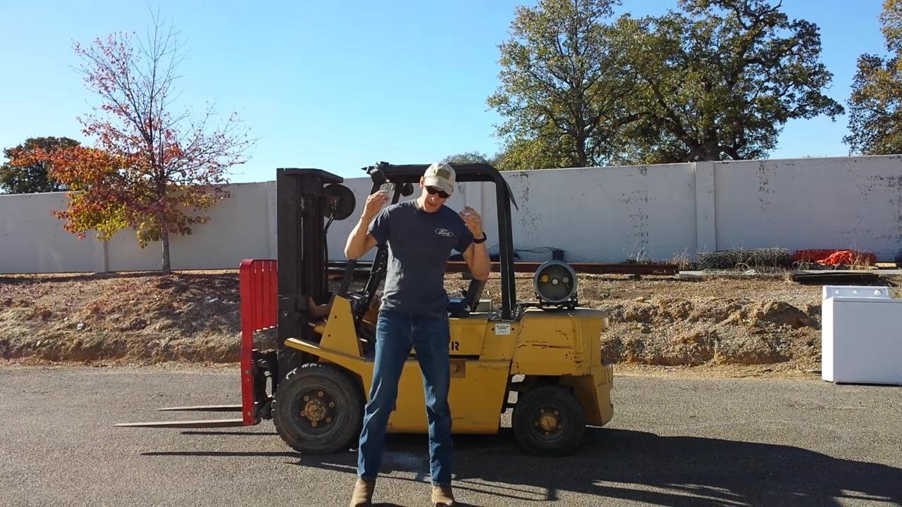 A person stands in front of a yellow HYSTER forklift, gesturing while introducing the tutorial. The forklift is parked outdoors, with its forks visible and a propane tank mounted at the rear.