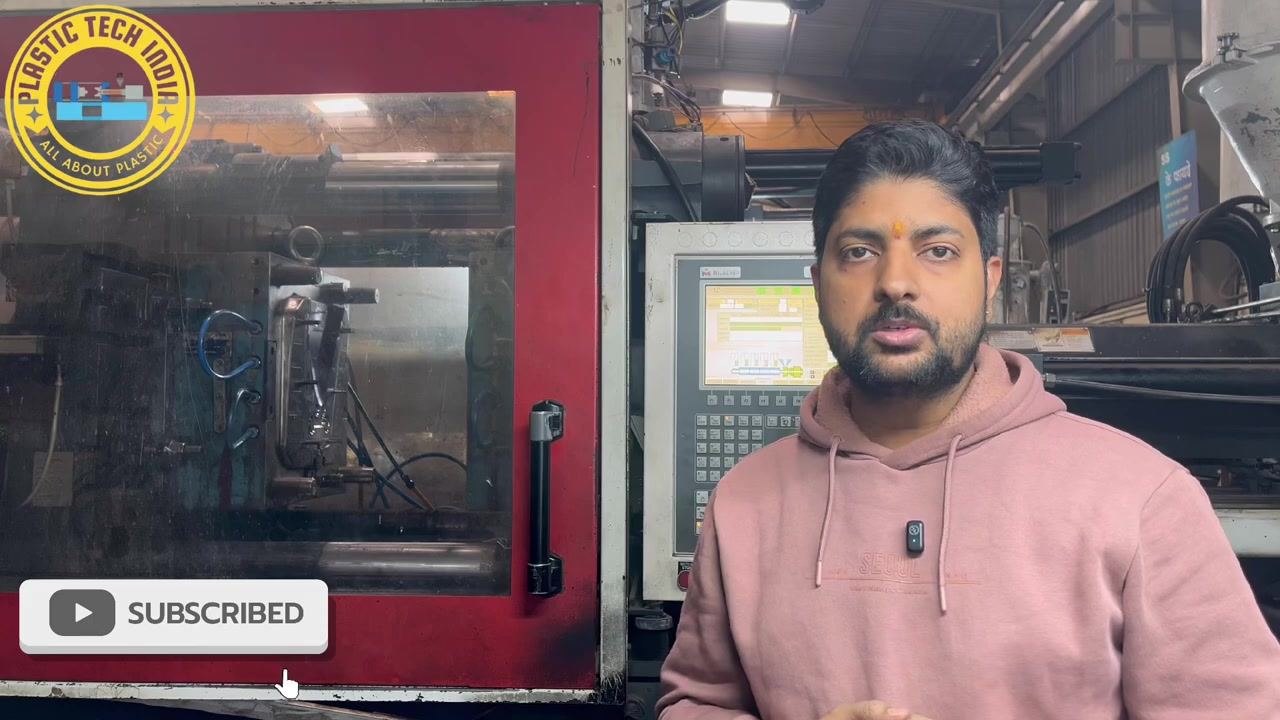 Presenter explaining the short mold problem while standing beside the injection molding machine and its control panel.