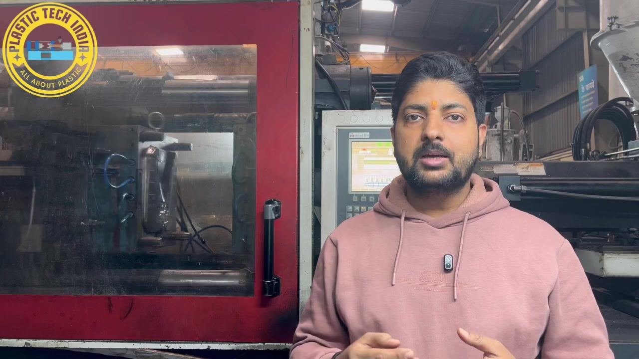 Presenter explaining the impact of nozzle leakage on short molding, standing beside the injection molding machine and control panel.