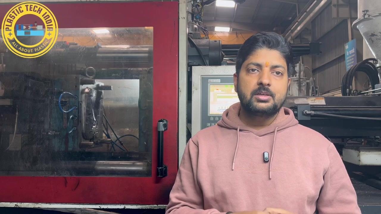 Presenter listing the systematic troubleshooting points, with the injection molding machine and control panel in the background.