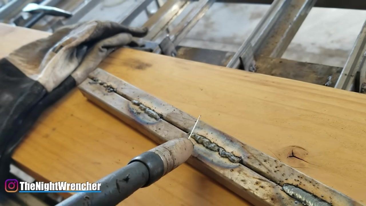 MIG gun tip and wire shown above the weld bead, demonstrating correct stick-out distance.