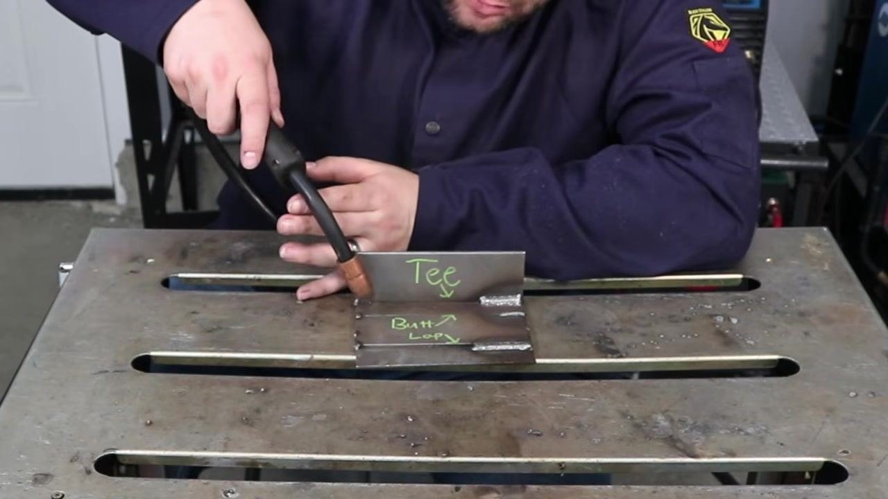 Person demonstrating MIG gun angle toward the "Tee" joint, emphasizing the importance of correct angles to avoid spatter