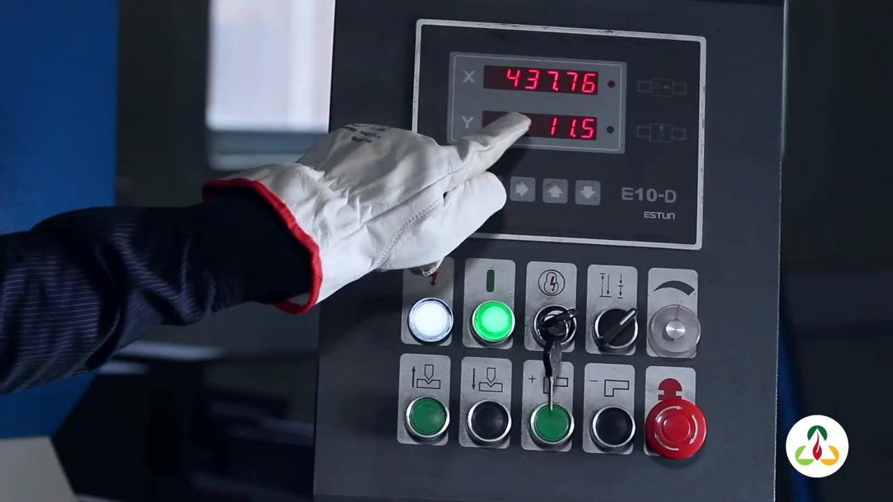Operator's gloved hand pointing at the control panel display, emphasizing the Y value.