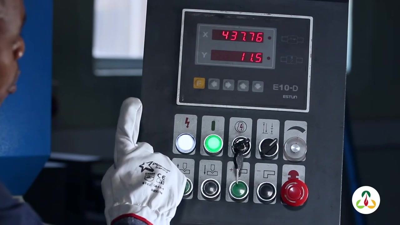 Operator's gloved hand pressing the control panel button, with the display showing the current values