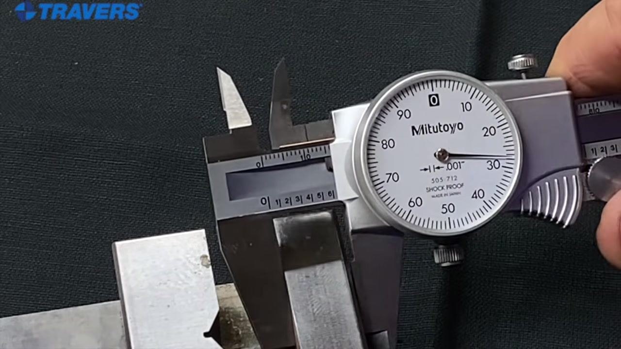 Close-up of a Mitutoyo dial caliper showing both inch and millimeter markings, with the dial reading in thousandths of an inch.