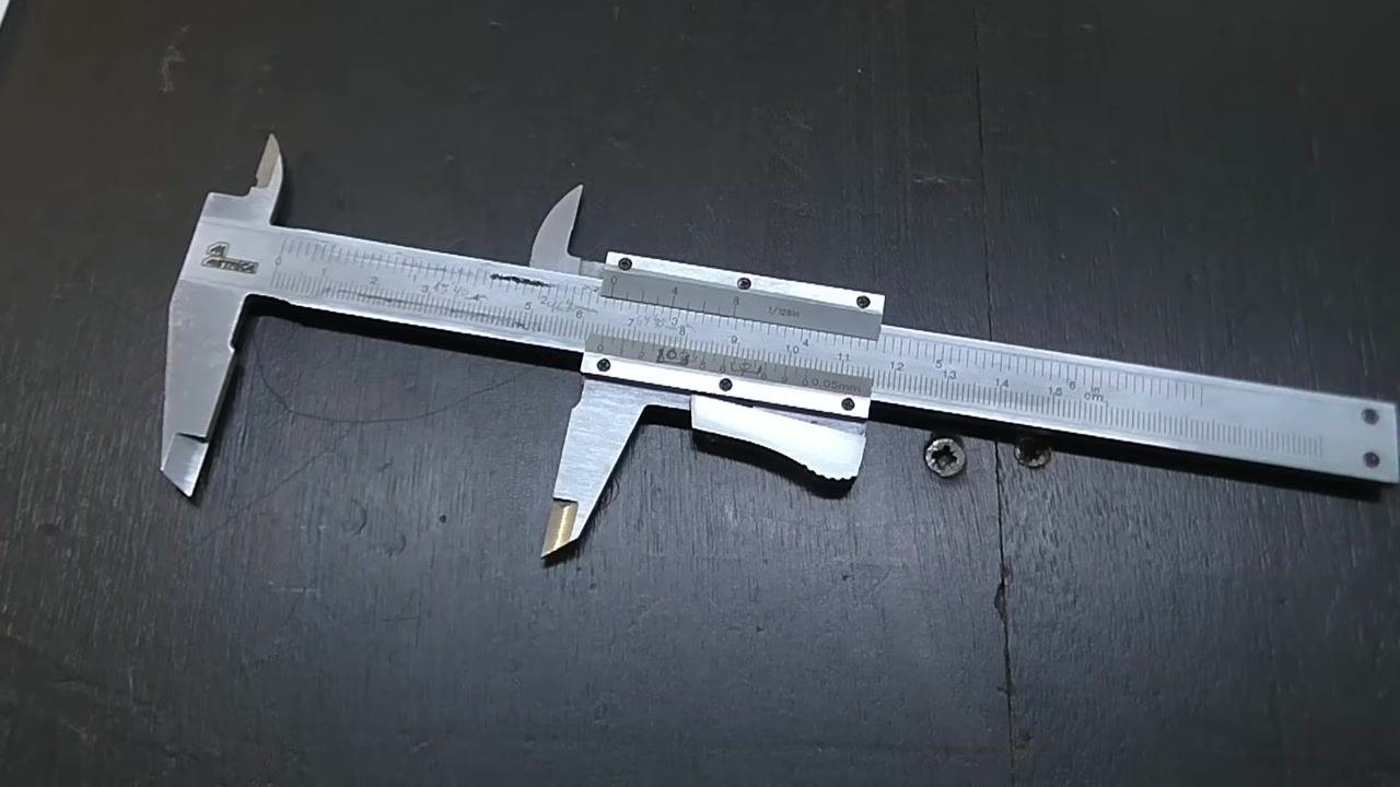 A pen points at the 7th line on the vernier scale to confirm the reading, with both scales visible.