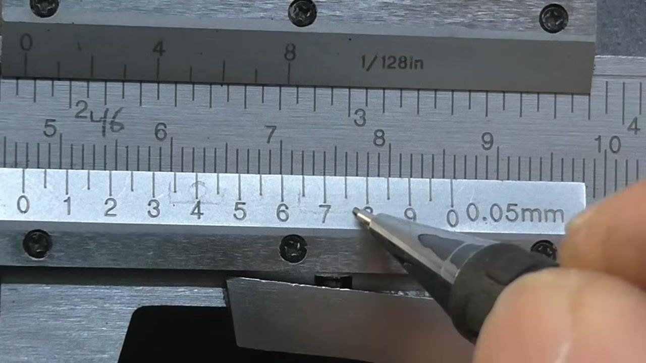Vernier caliper with the vernier scale zero just past the 46 mm mark on the main scale, indicated by a pen.