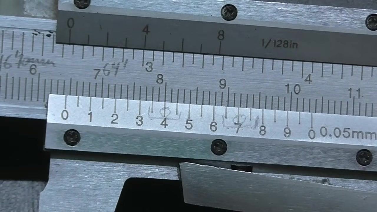 Close-up of a vernier caliper showing three lines on the vernier scale aligned with the main scale, with no hand or pointer present.