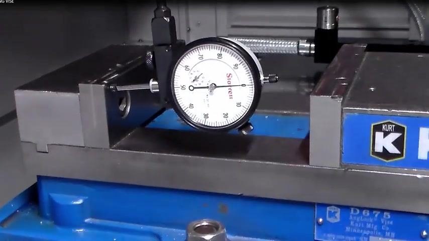 Dial indicator in position, vise ready for tapping adjustment, blue vise base and Kurt branding visible