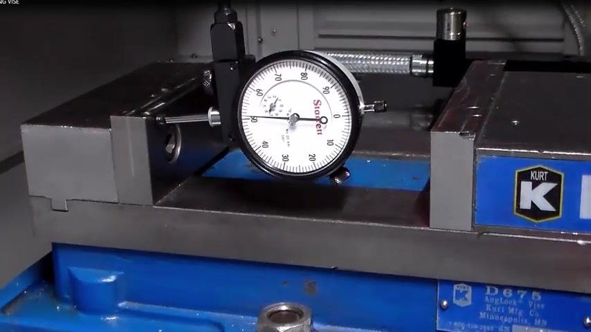Starrett dial indicator zeroed on the solid jaw of a Kurt vise, blue vise base visible, confirming final alignment