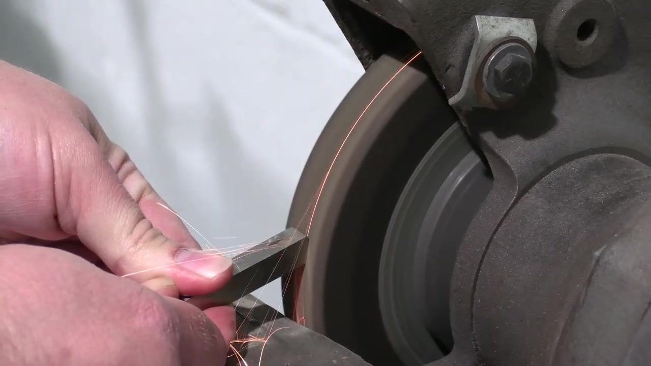 The tool bit is held against the grinding wheel as grinding continues.
