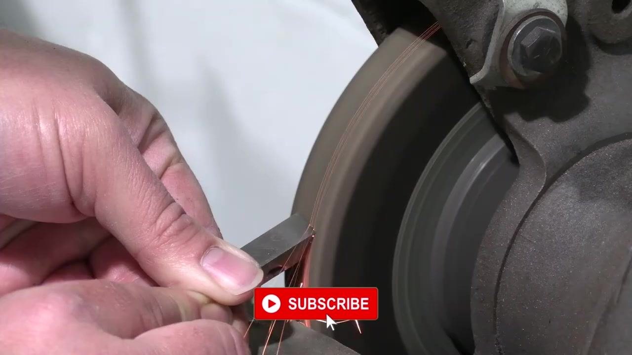 The tool bit is held against the grinding wheel with visible sparks, positioned for final shaping.