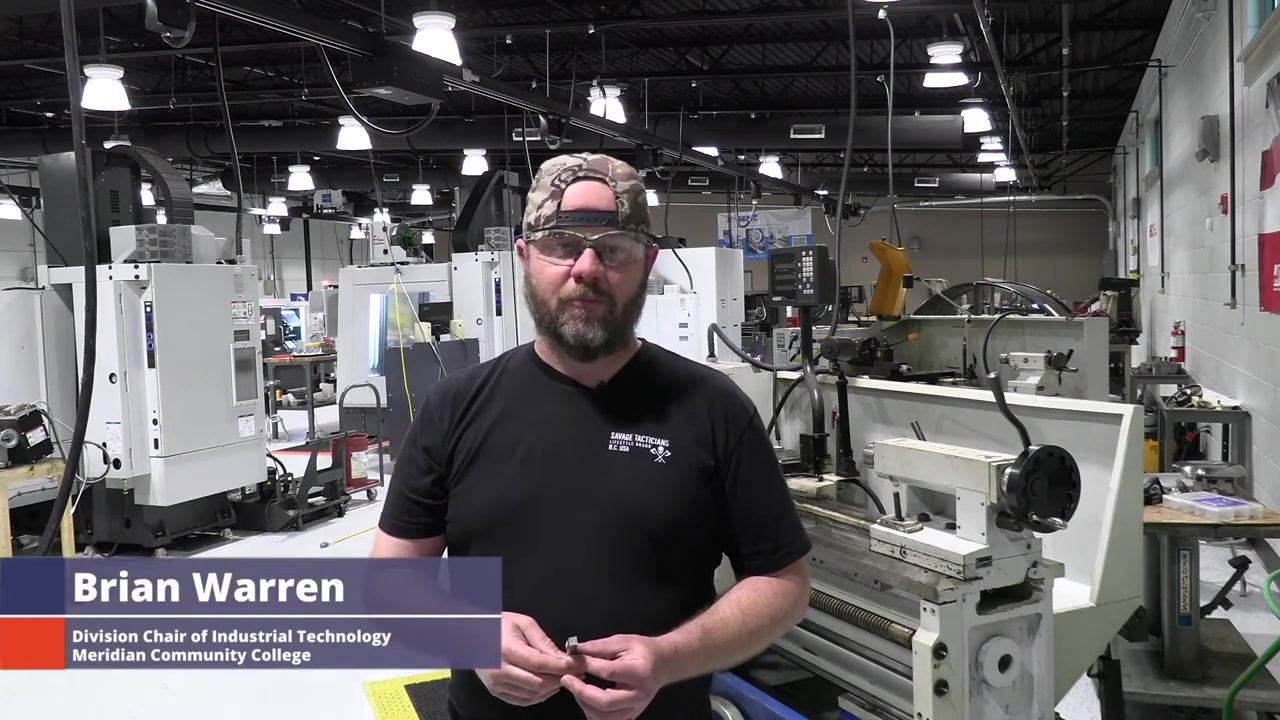 Brian Warren introduces the topic in a machine shop, standing in front of a lathe and other industrial equipment. On-screen text identifies him and his role.