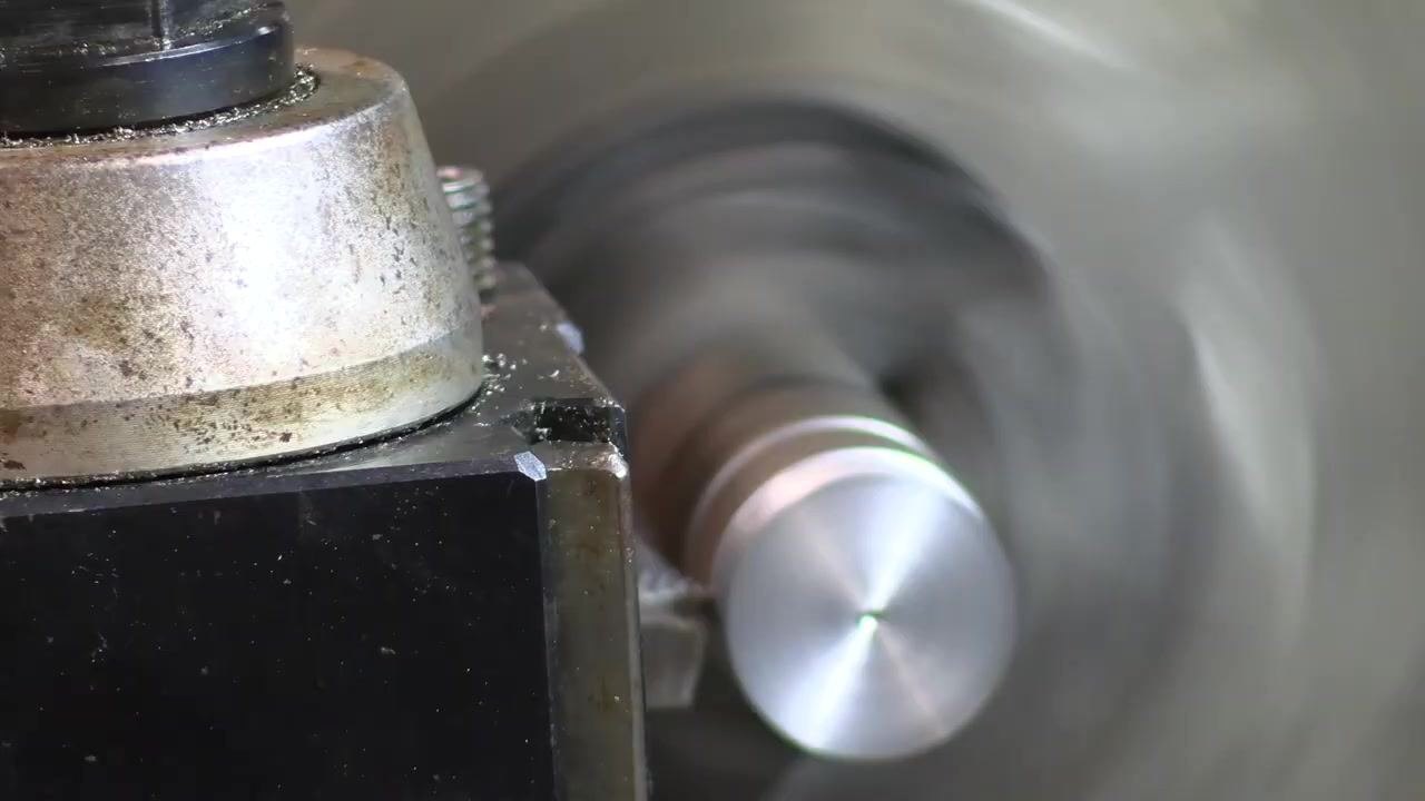 The lathe operation continues with chips forming and the tool post in focus.