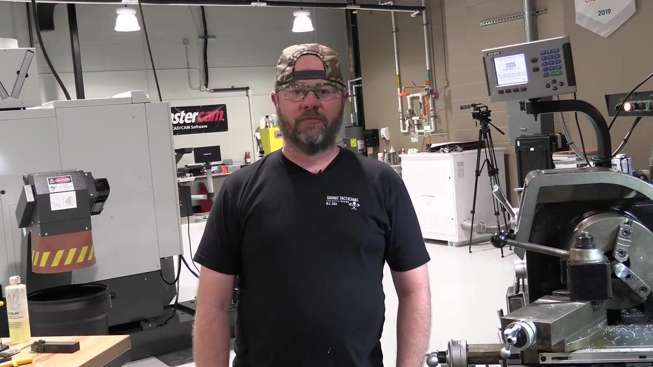Operator standing in a machine shop, inviting feedback or comments from viewers.
