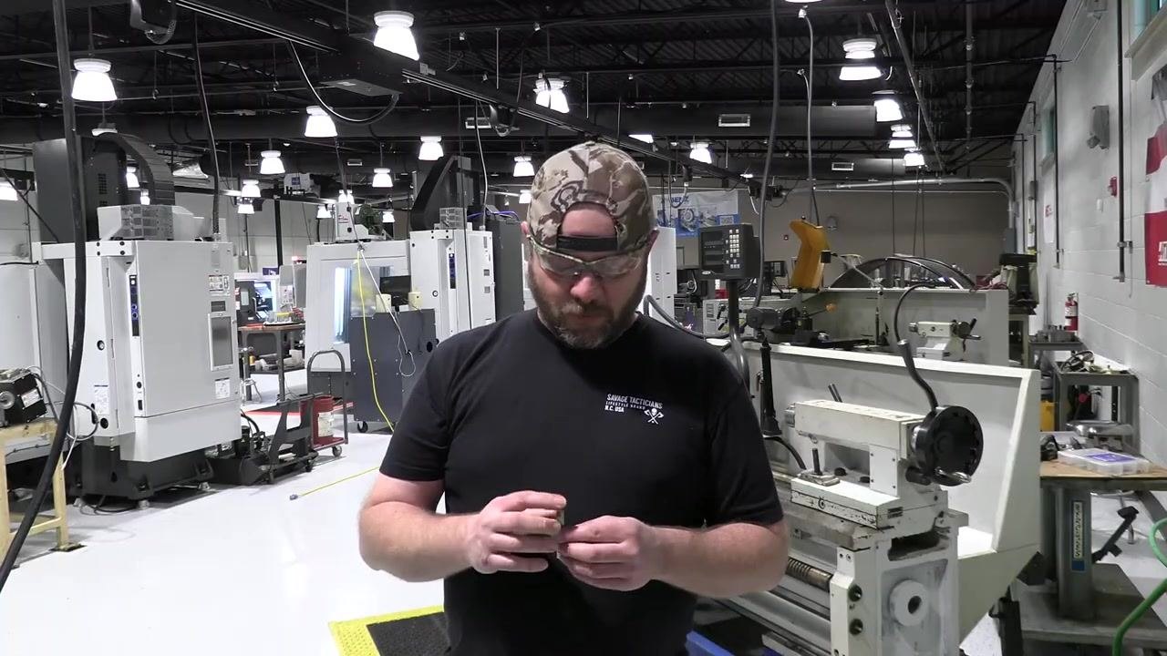 Hands hold a high-speed steel tool bit at the bench grinder, preparing to begin the grinding process.