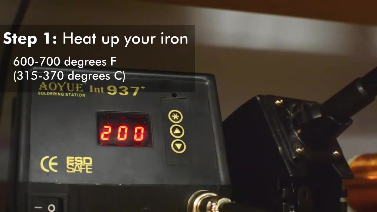 Close-up of a soldering station dial set to the recommended temperature range, with on-screen text: "Step 1: Heat up your iron. 600–700 degrees F (315–370 degrees C)"