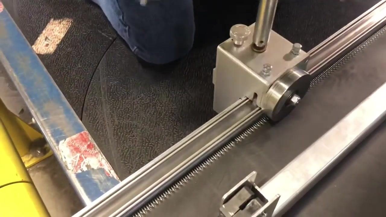 The end of the lacing machine with a black handle and yellow safety rail visible, indicating readiness to remove the rod.