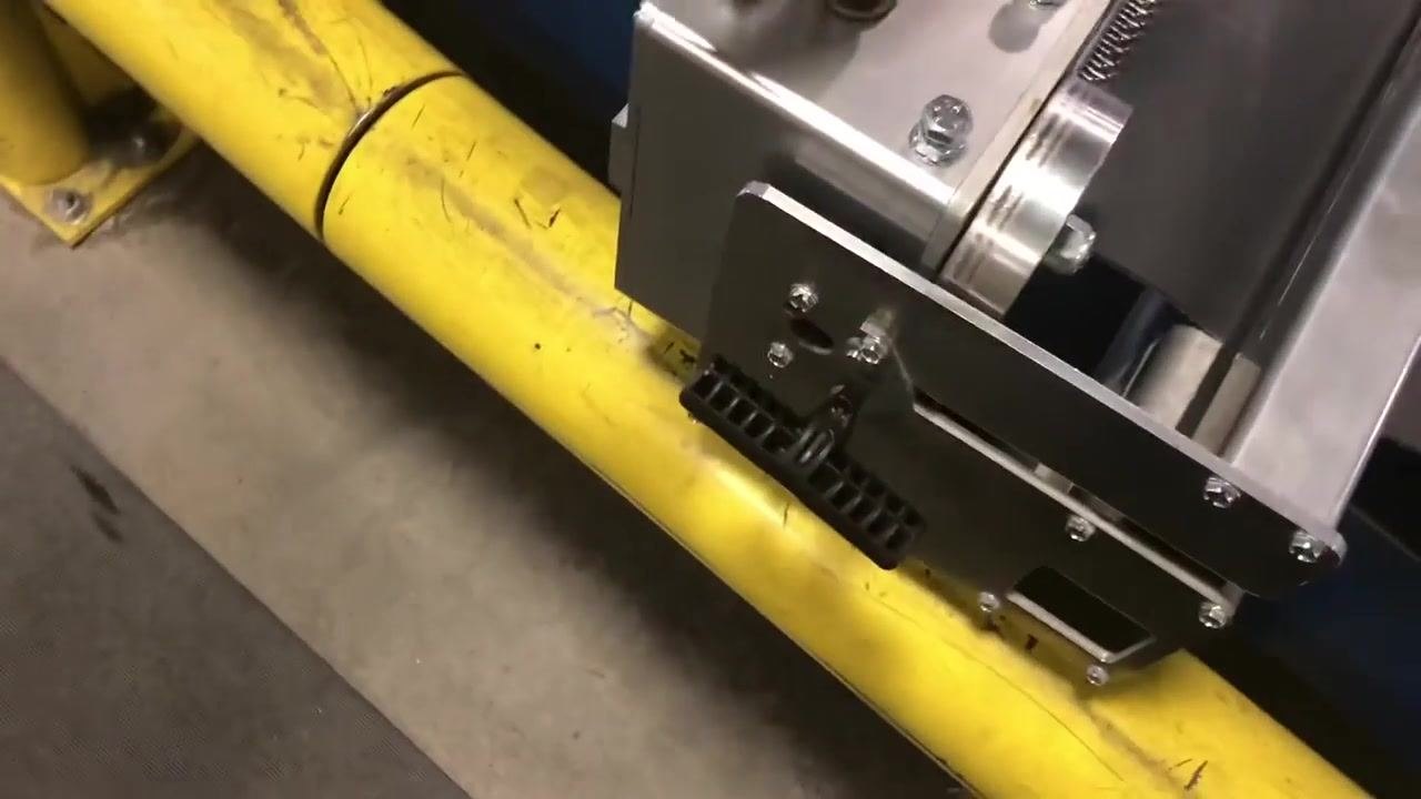 A hand holding the finished laced belt, showing the row of metal hooks securely attached to the edge. The lacing machine and the "ROLLER LACER" label are visible in the background.