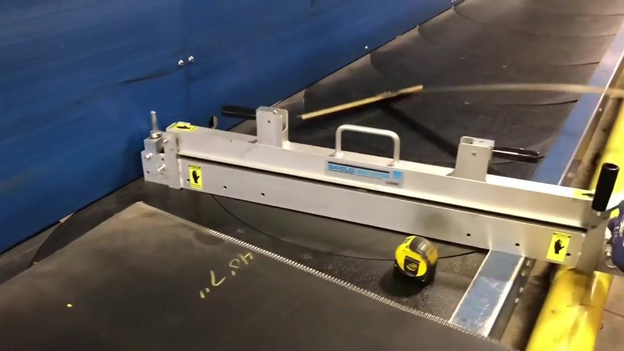 The belt cutter is positioned across the conveyor belt, with a tape measure and t-square visible.