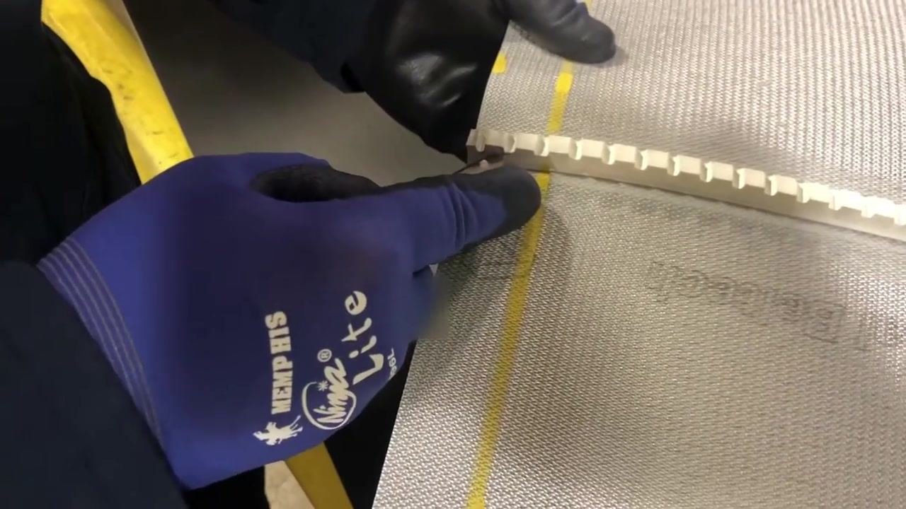 A close-up of the lacing machine with hooks installed, one hook is incorrectly oriented (face down).