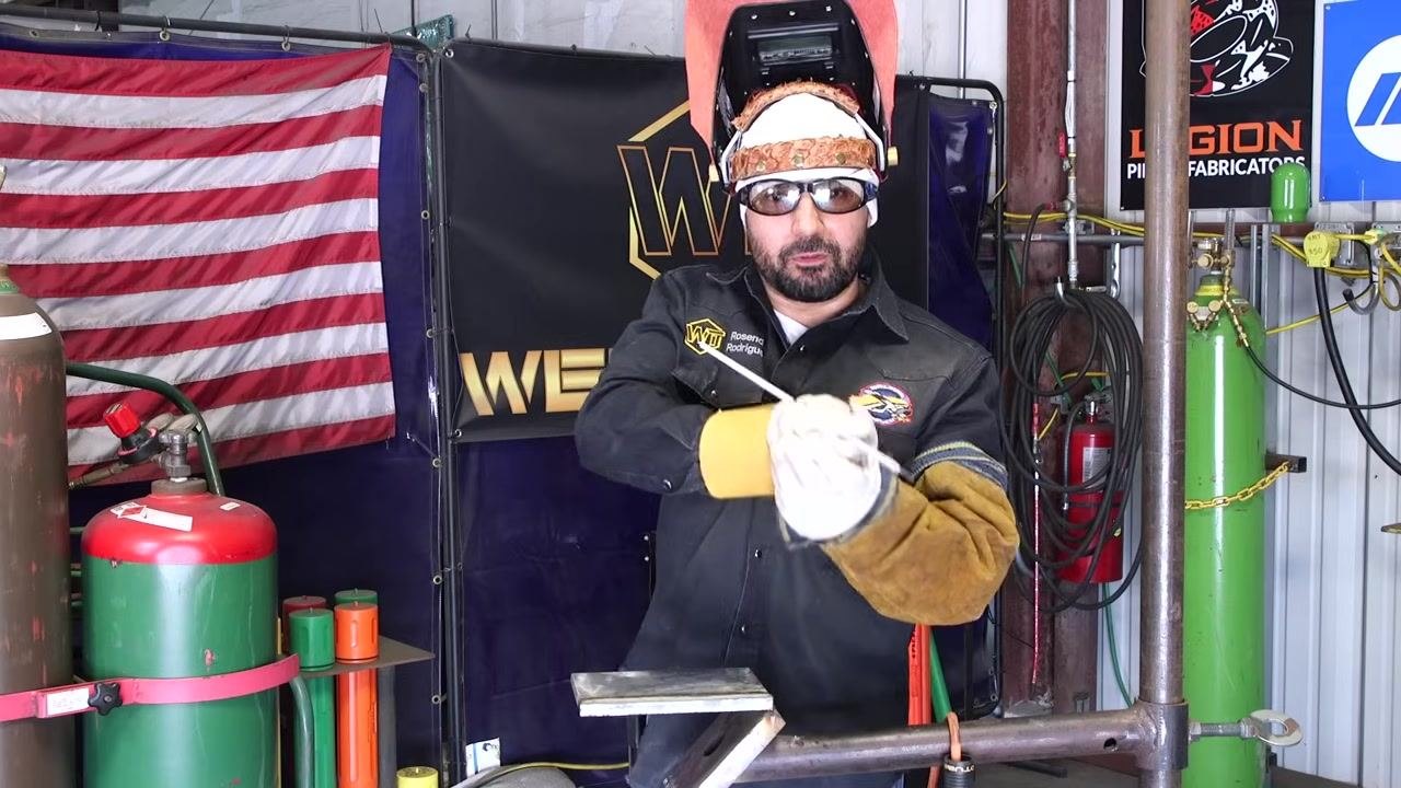 Hand position for starting a new weld bead is demonstrated, with the rod held in both hands in front of the workpiece.