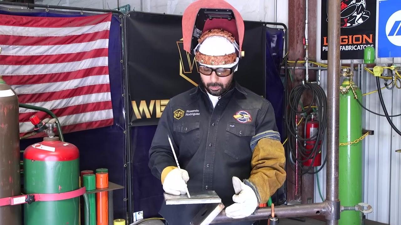 A welder stands at the station, looking down and preparing to demonstrate a proper restart technique.