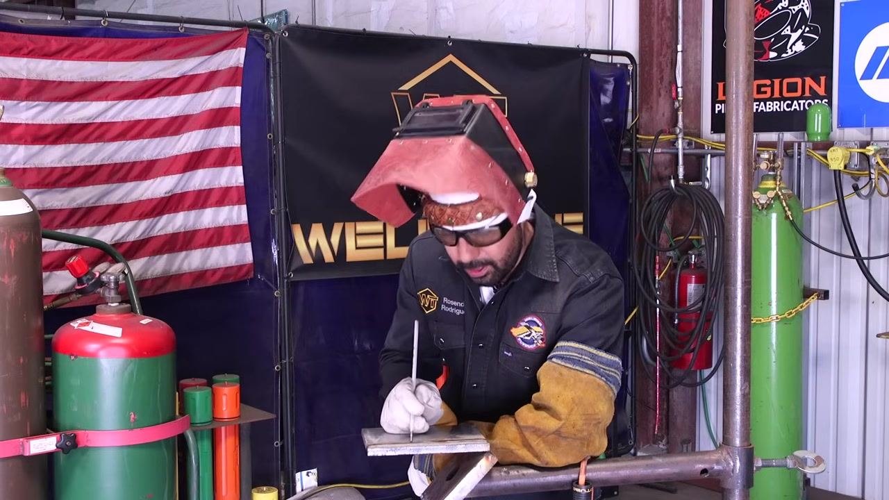 The welding rod is held above the workpiece to demonstrate arc control.