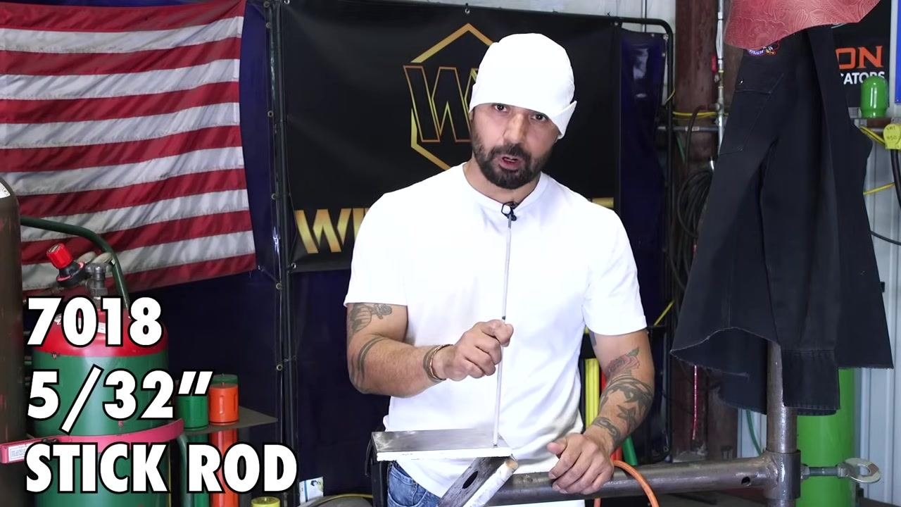 Hands position the stick rod to feed it into the weld puddle, demonstrating proper feeding technique.
