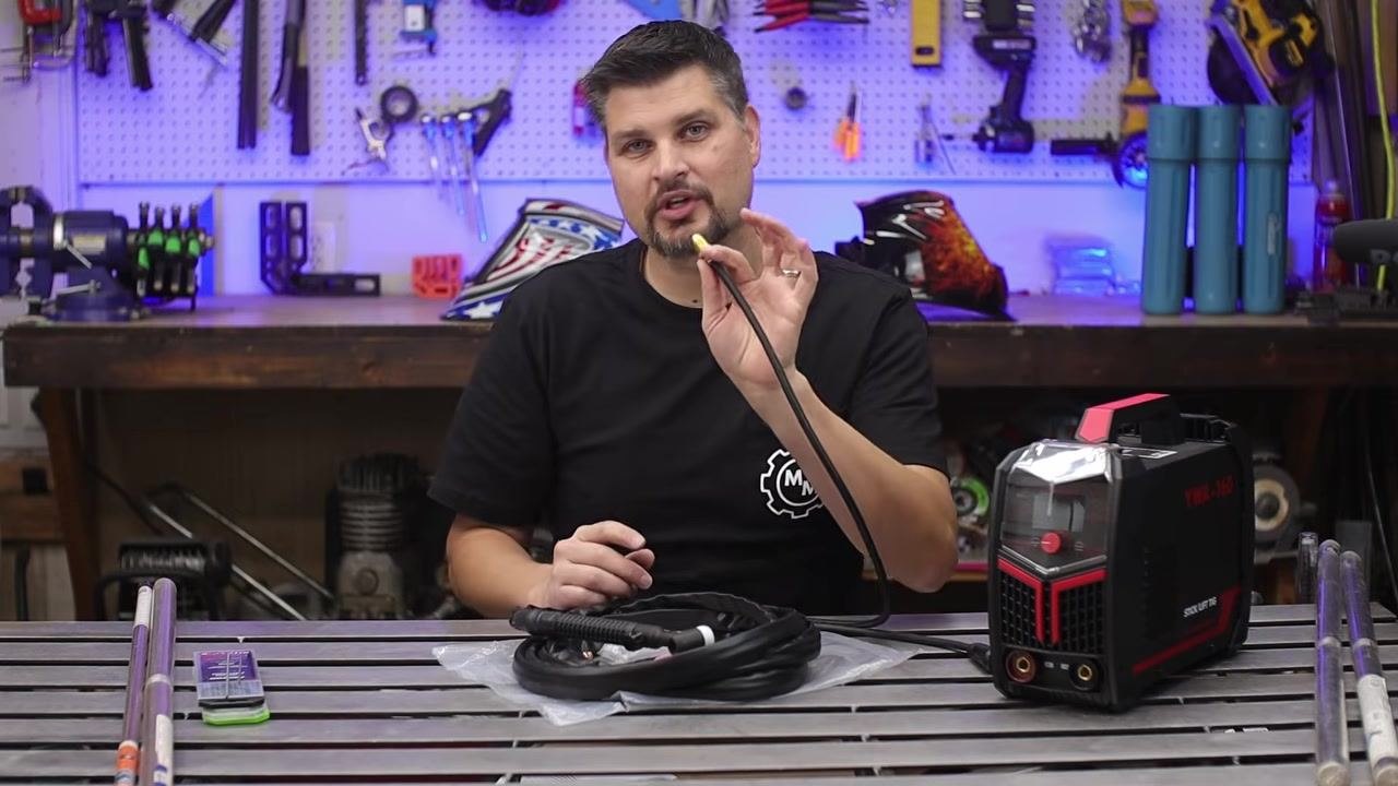 Person holding the gas input fitting of a TIG torch hose, showing its connection point to the gas regulator or flow meter.