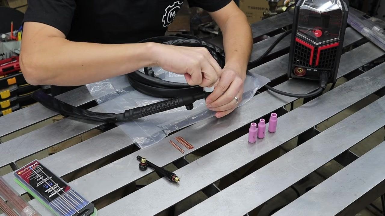 Hand holding up a back cap next to the TIG torch and other components, illustrating its role in the assembly.