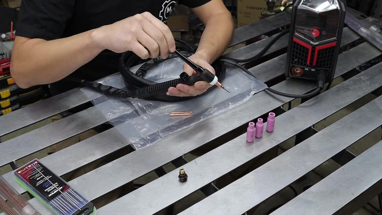 Hands inserting the tungsten electrode and threading the back cap onto the TIG torch.