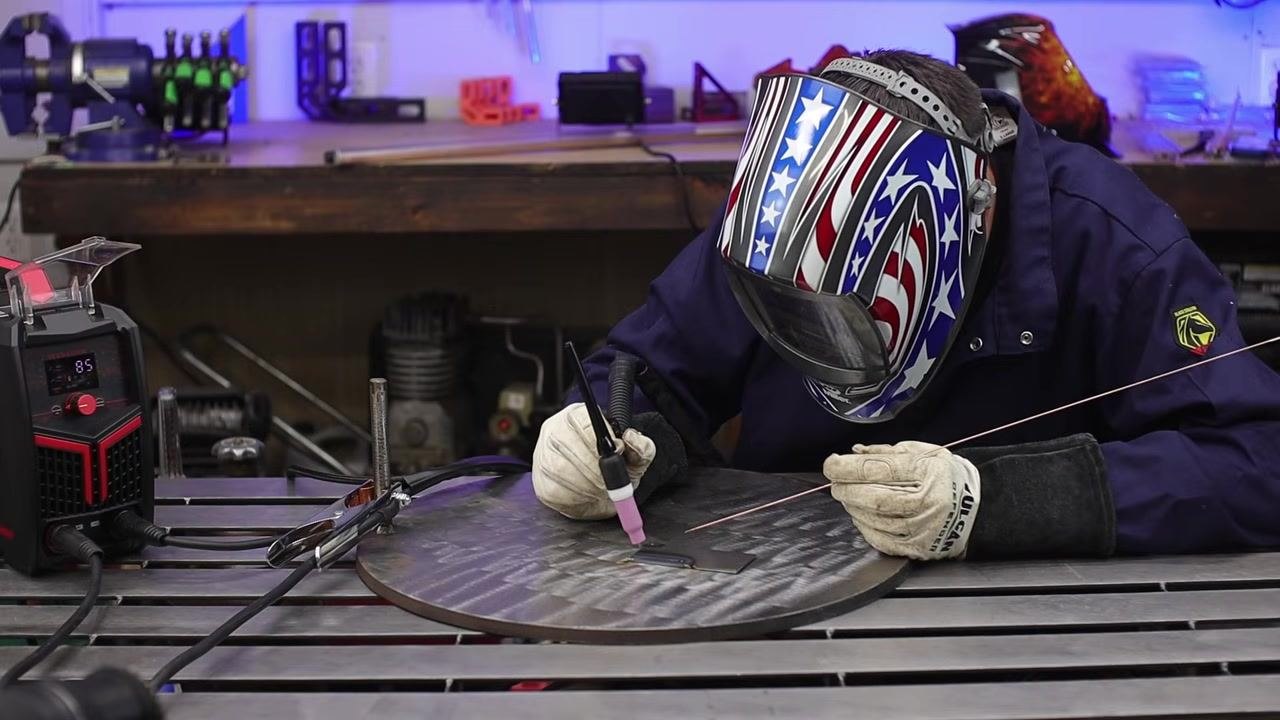 Welder finishing a weld with the arc still visible and filler rod in hand, maintaining control at the end of the weld.