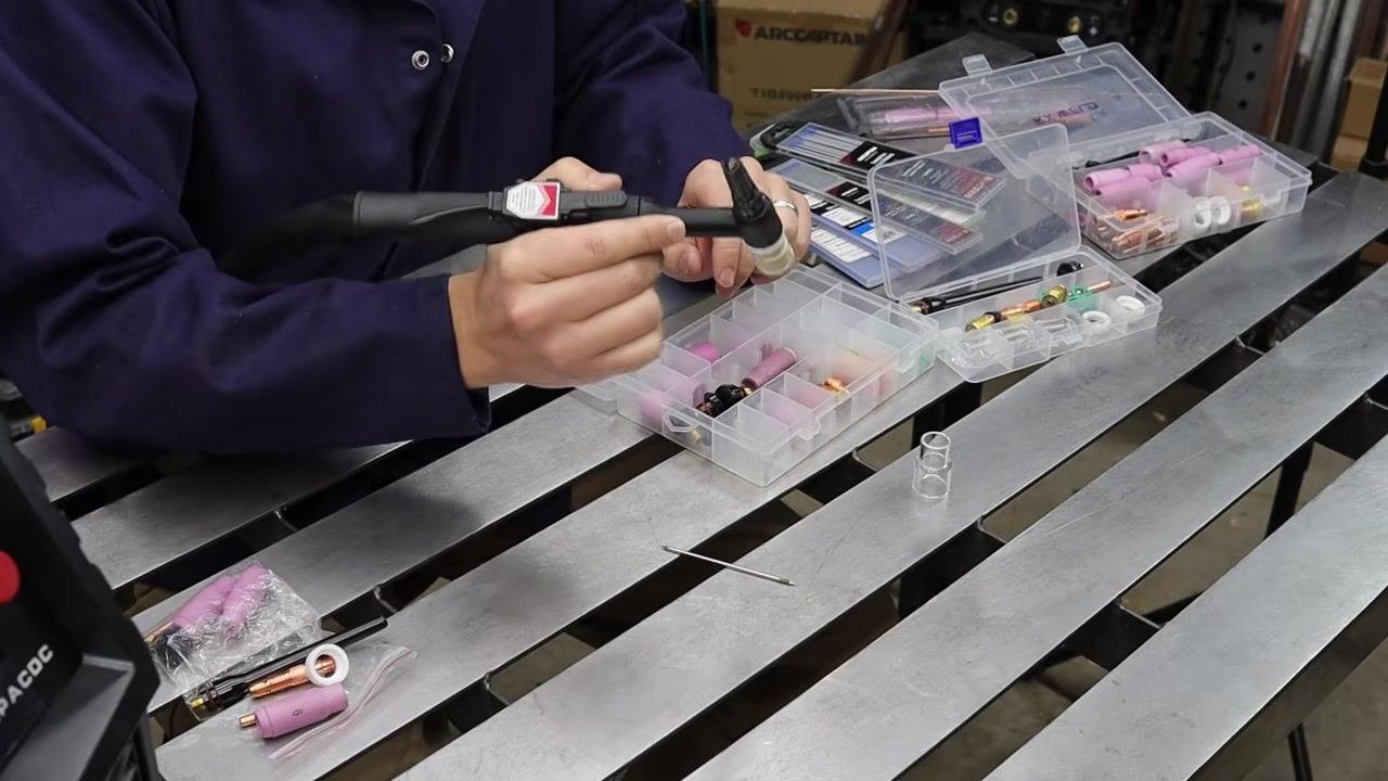 Person demonstrating the close proximity of the stubby-equipped torch to the workpiece, with TIG accessories visible.
